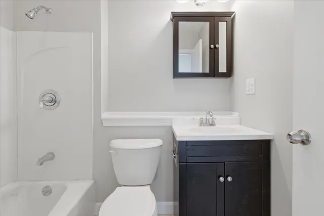 a bathroom with a toilet a sink a mirror a bathtub and vanity