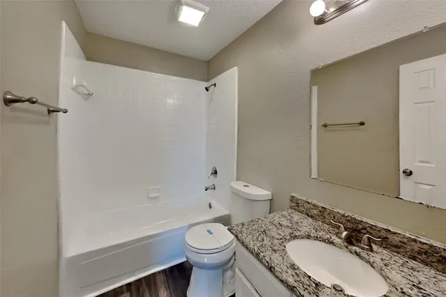 a bathroom with a granite countertop toilet a sink and a bathtub