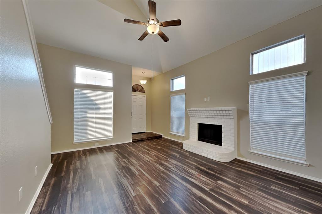 921 Mossberg Lane Mesquite, TX 75181 - Photo 4 of 17 Unfurnished living room with dark wood-type flooring, a ceiling fan, high vaulted ceiling, a brick fireplace, and plenty of natural light