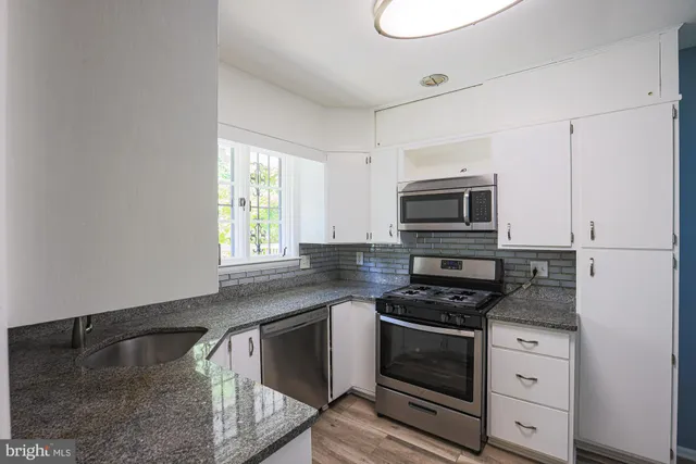 a kitchen with granite countertop a stove and a microwave