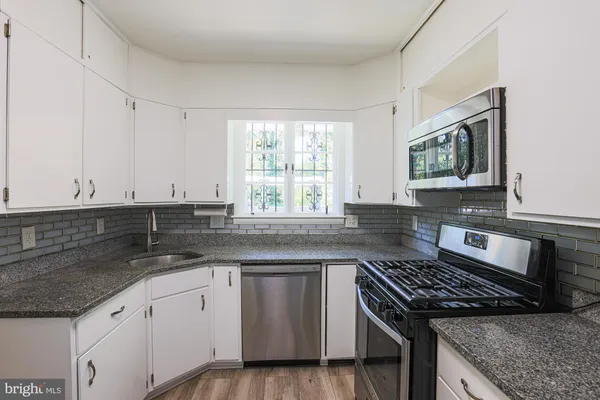 a kitchen with granite countertop a sink stove and cabinets