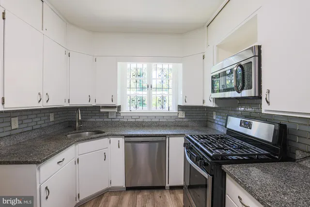 a kitchen with granite countertop a sink stove and cabinets