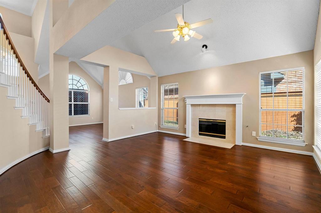 14588 Poe Court Addison, TX 75001 - Photo 4 of 28 an empty room with wooden floor fireplace and windows