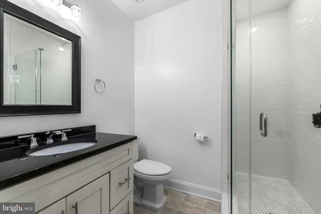 a bathroom with a granite countertop sink toilet and shower