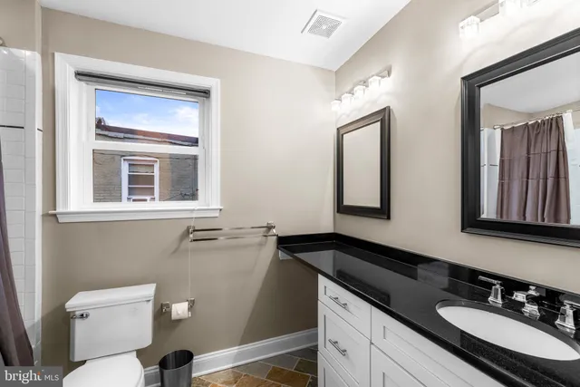 a bathroom with a granite countertop sink mirror and toilet