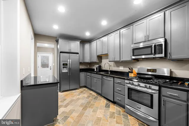 a kitchen with stainless steel appliances granite countertop a refrigerator a stove top oven a sink and dishwasher