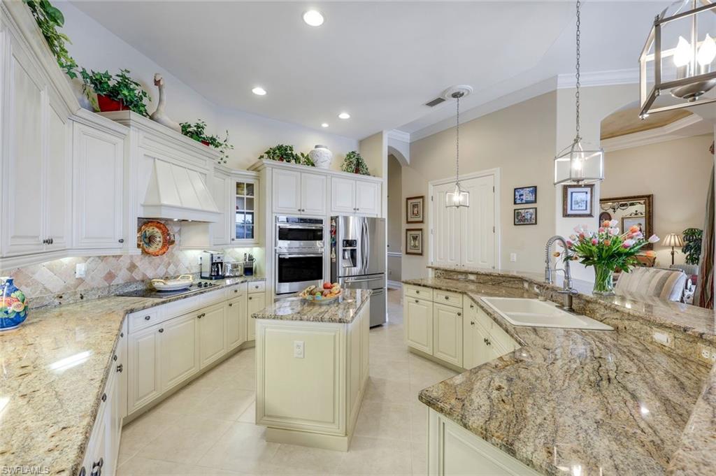 8993 Crooked Stick Court Naples, FL 34113 - Photo 4 of 24 a large kitchen with granite countertop a sink stove and refrigerator