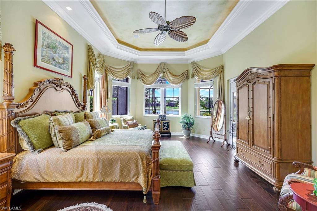 8993 Crooked Stick Court Naples, FL 34113 - Photo 10 of 24 a spacious bedroom with a bed a window and a chandelier