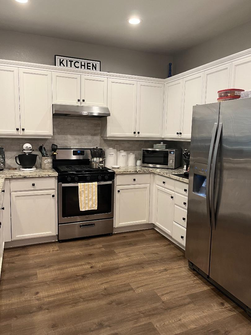 4184 Ivory Lane Turlock, CA 95382 - Photo 4 of 11 a kitchen with stainless steel appliances granite countertop a stove a sink and a refrigerator