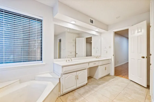 a large bathroom with a large tub sink vanity and granite