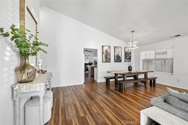 a living room with furniture a potted plant and open kitchen view