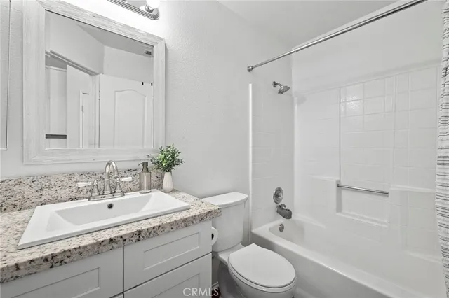 a bathroom with a granite countertop sink a toilet and shower