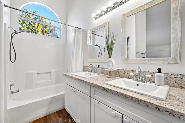 a bathroom with a granite countertop sink mirror and a bathtub