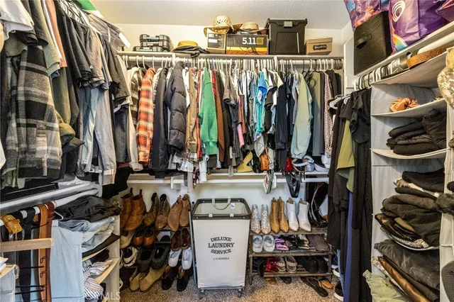 a view of walk in closet with clothes and shoes