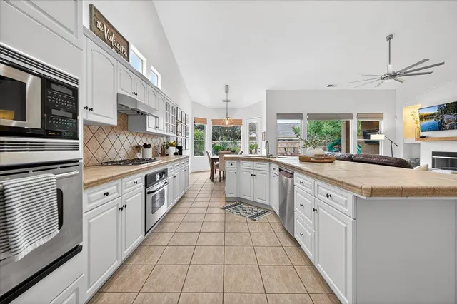 a large white kitchen with stainless steel appliances granite countertop a stove a sink and a microwave