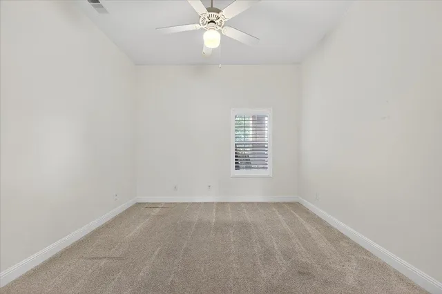 an empty room with a window and a fan