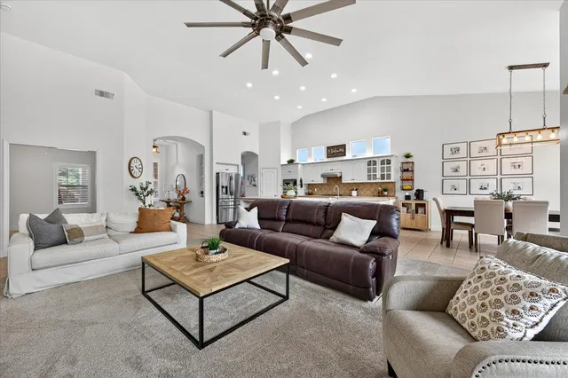 a living room with furniture kitchen view and a chandelier
