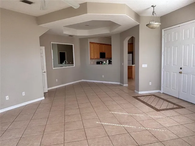 a view of an empty room with window and chandelier fan