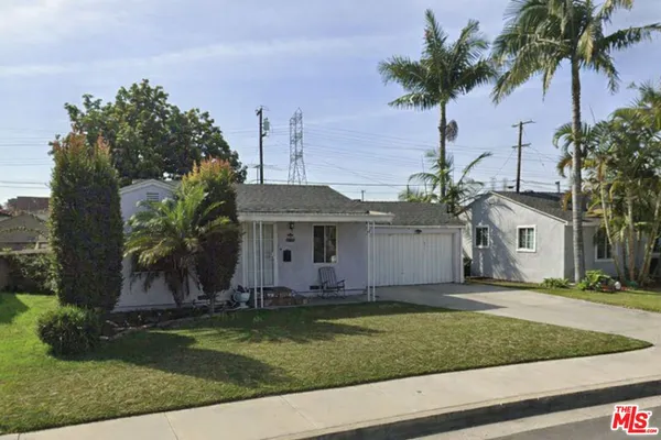 a front view of a house with a yard and palm trees