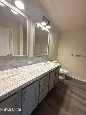a bathroom with a granite countertop sink a toilet a large mirror and vanity