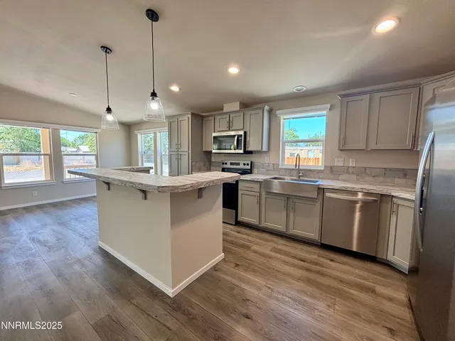 a kitchen with stainless steel appliances granite countertop a white cabinets a sink a stove a refrigerator and island with wooden floor