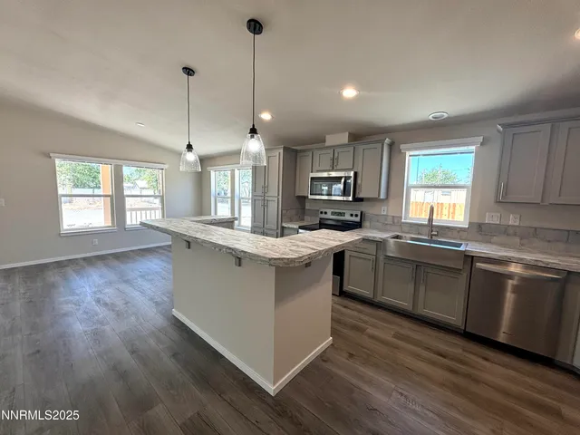 a kitchen with stainless steel appliances granite countertop a sink a stove and wooden floor