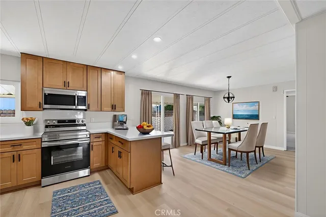 a kitchen with stainless steel appliances granite countertop a stove top oven a sink dishwasher and a refrigerator with wooden floor