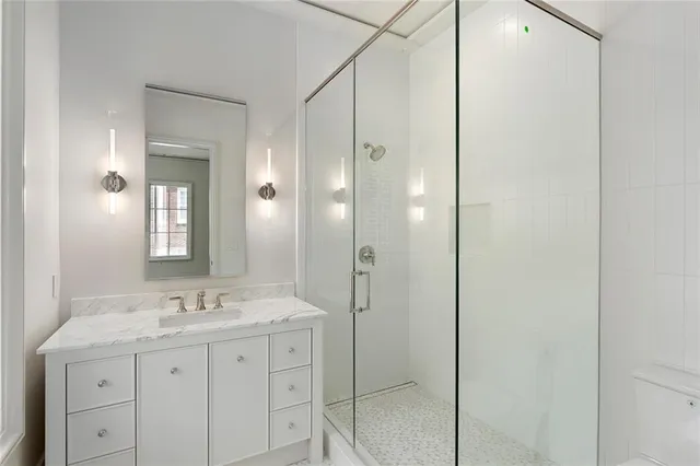 a bathroom with a granite countertop sink a toilet and shower