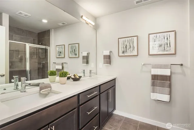 a bathroom with double vanity sinks a mirror and a shower