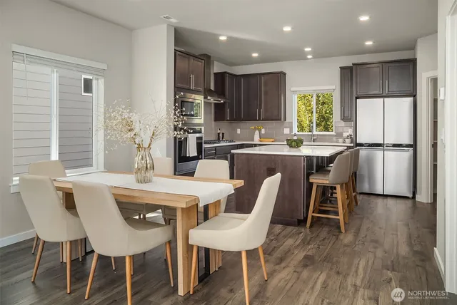 a dining room with stainless steel appliances kitchen island granite countertop a dining table chairs and a refrigerator