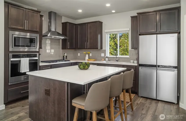a kitchen with kitchen island a counter space a sink appliances and cabinets