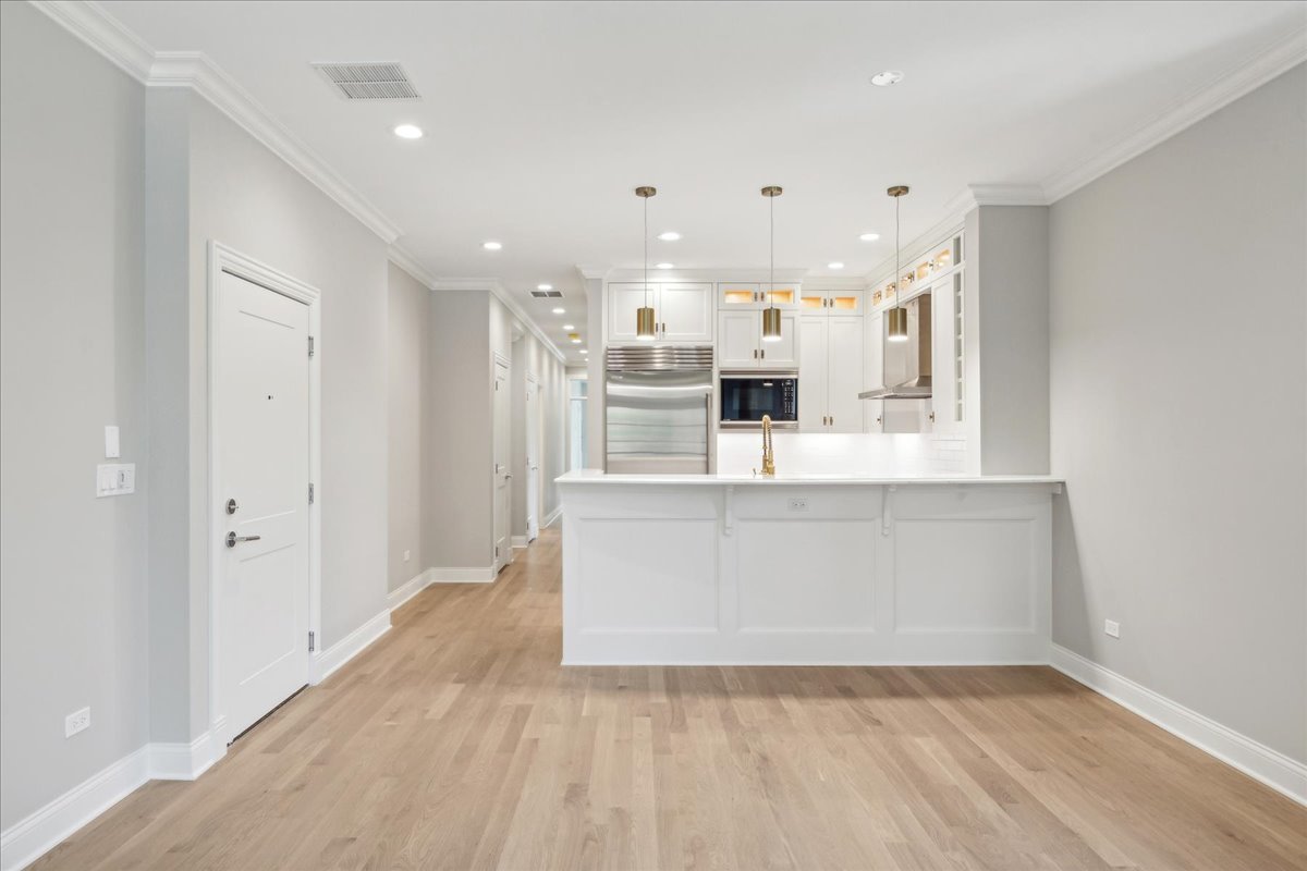1457 West Roscoe Street, Unit 2 Chicago, IL 60657 - Photo 4 of 16 a view of kitchen with kitchen island white cabinets and refrigerator