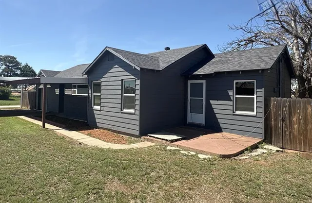 a view of a house with a small yard and wooden fence