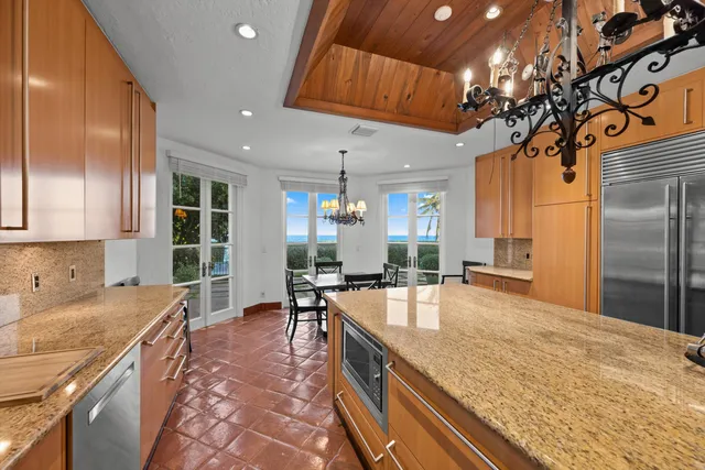 a large kitchen with kitchen island a large counter top stainless steel appliances and cabinets