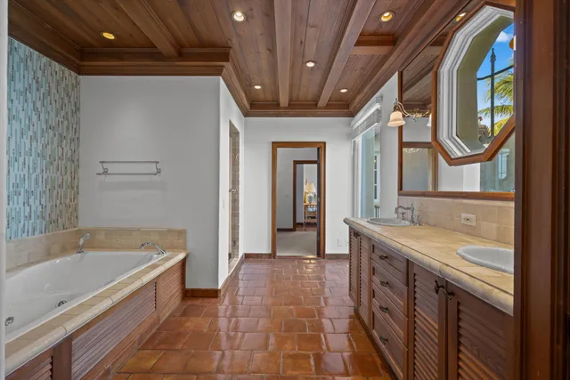 a spacious bathroom with a tub a double vanity sink and a mirror