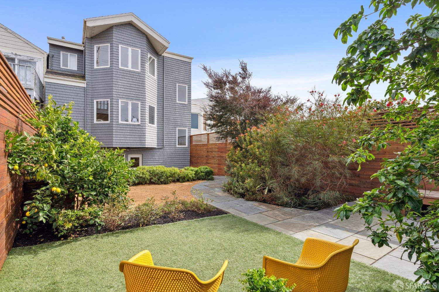 a view of a white house with a big yard and potted plants