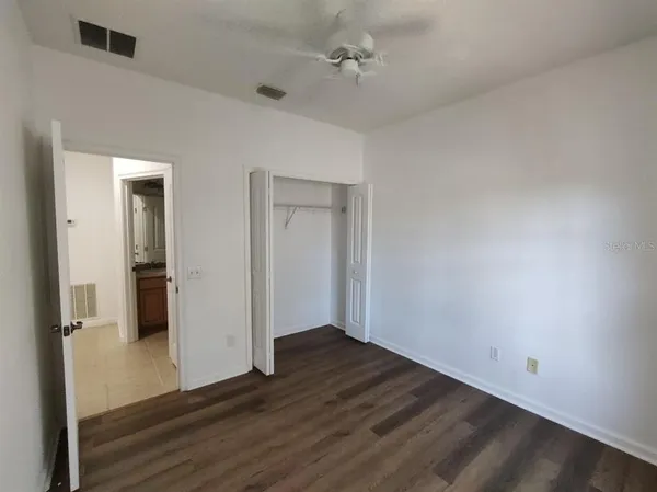 an empty room with wooden floor and a ceiling fan