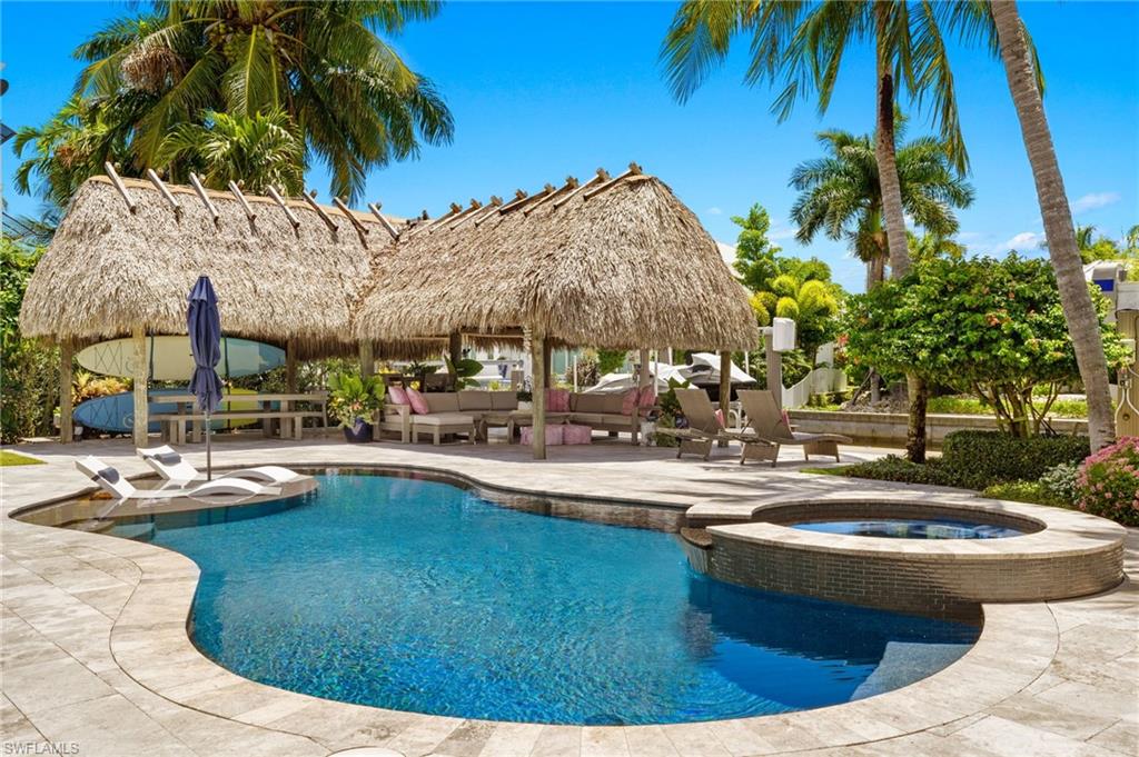 1960 Tarpon Road Naples, FL 34102 - Photo 43 of 49 a view of a swimming pool with a lawn chairs under palm trees