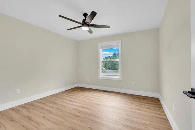 a view of empty room with wooden floor and fan