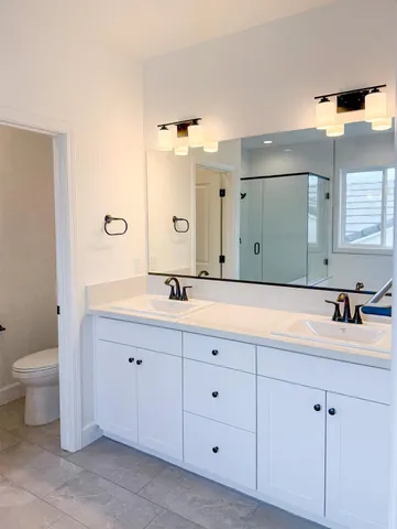 a bathroom with a double vanity sink mirror and toilet
