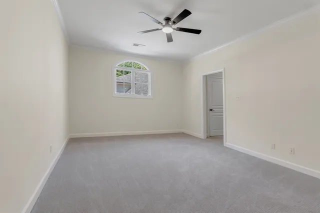 an empty room with a chandelier fan and windows