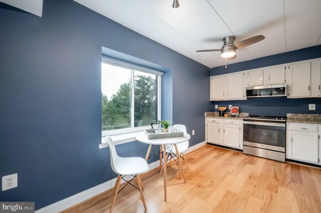 a kitchen with stainless steel appliances kitchen island granite countertop a stove top oven a sink a dining table and chairs with wooden floor