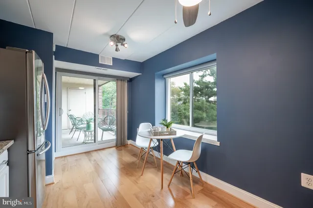 a dining room with furniture large windows wooden floor and a chandelier