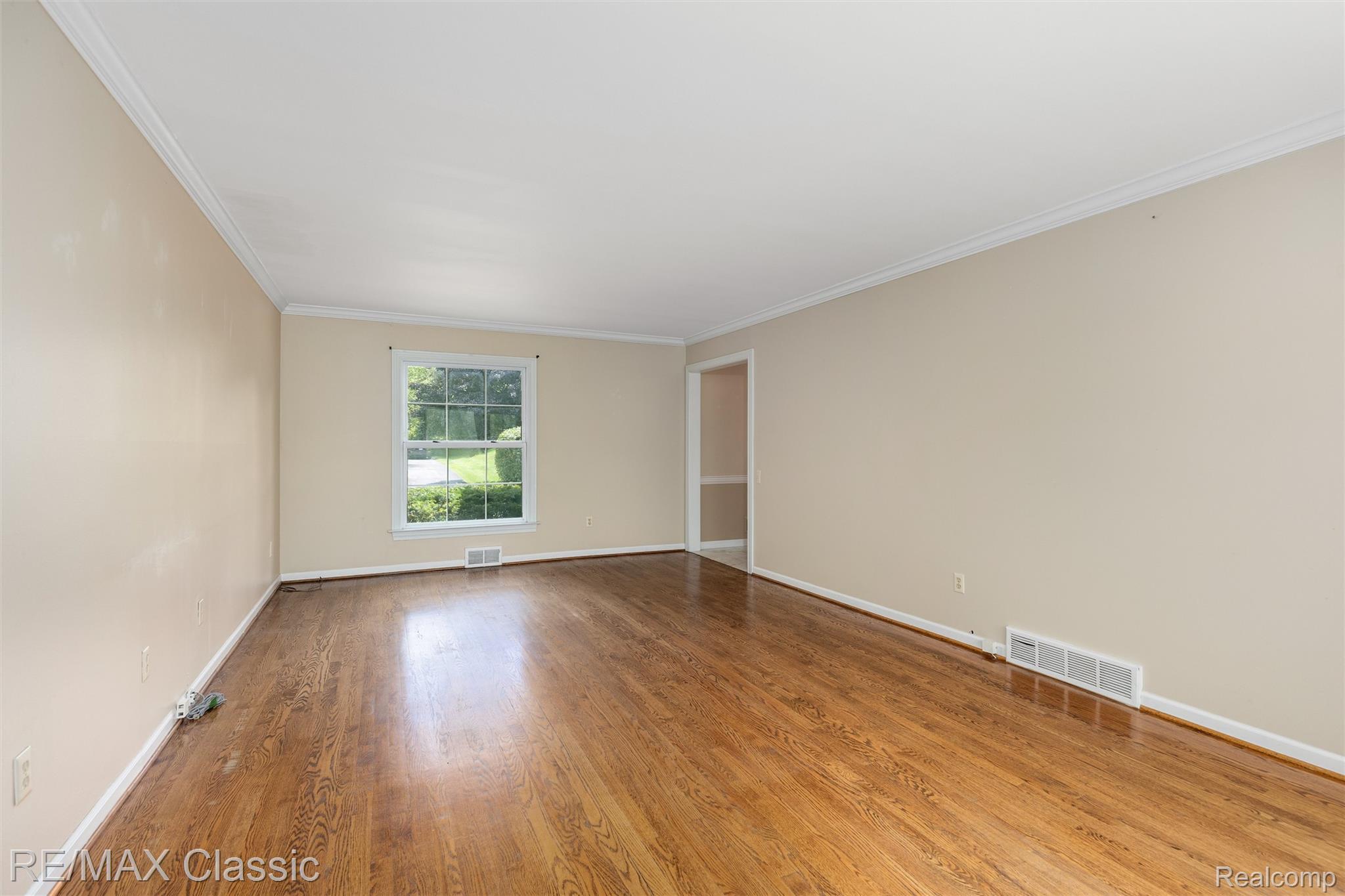 4268 Covered Bridge Road Bloomfield Hills, MI 48302 - Photo 11 of 35 Spacious room featuring wood-finish flooring, a large window, neutral wall tones, white crown molding, and white baseboards