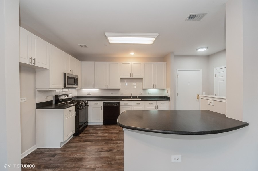 640 McHenry Road, Unit 203 Wheeling, IL 60090 - Photo 2 of 14 a kitchen with stainless steel appliances granite countertop a sink a stove top oven a counter space and cabinets