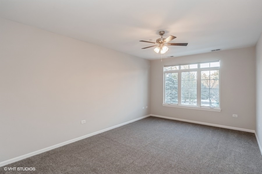 640 McHenry Road, Unit 203 Wheeling, IL 60090 - Photo 7 of 14 an empty room with a window and a ceiling fan