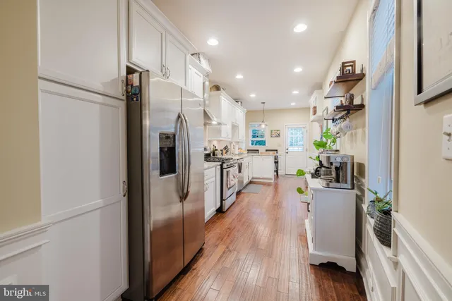 a view of a kitchen with refrigerator and wooden floor