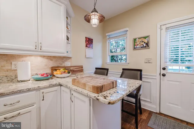 a kitchen with stainless steel appliances granite countertop a sink dishwasher and white cabinets with wooden floor