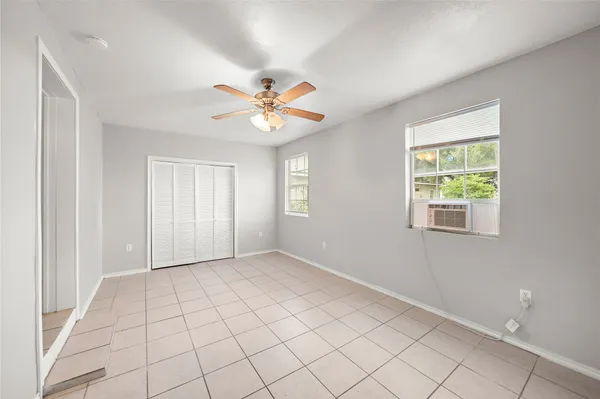 an empty room with windows and ceiling fan