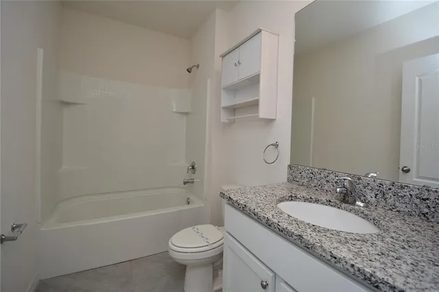 a bathroom with a granite countertop toilet and a sink
